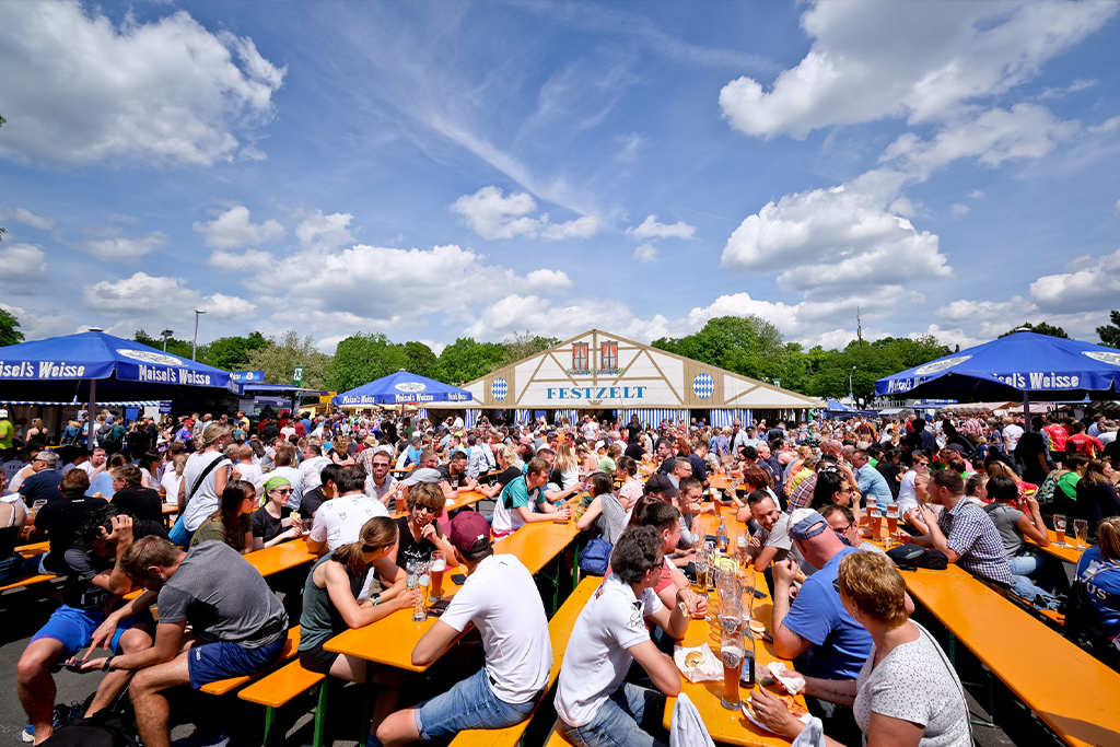 Menschen an Bierbänken vor dem Festzelt in der Übersicht